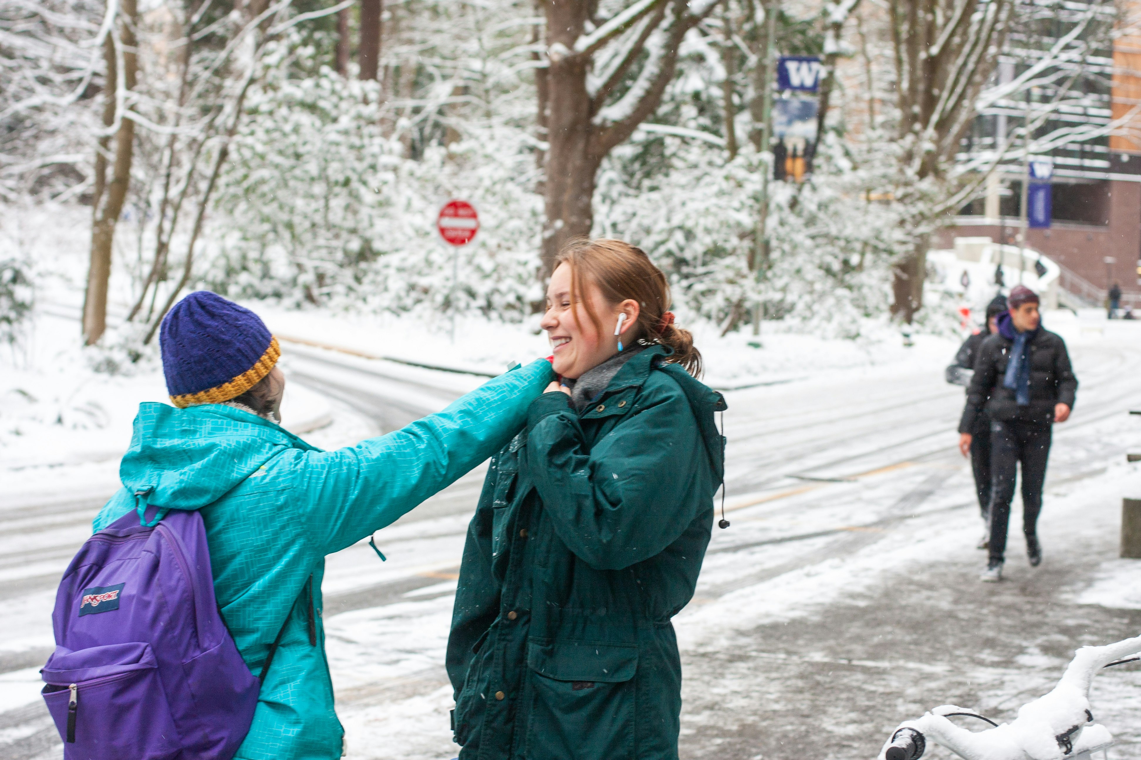 woman in green jacket and blue knit cap standing on snow covered ground during daytime